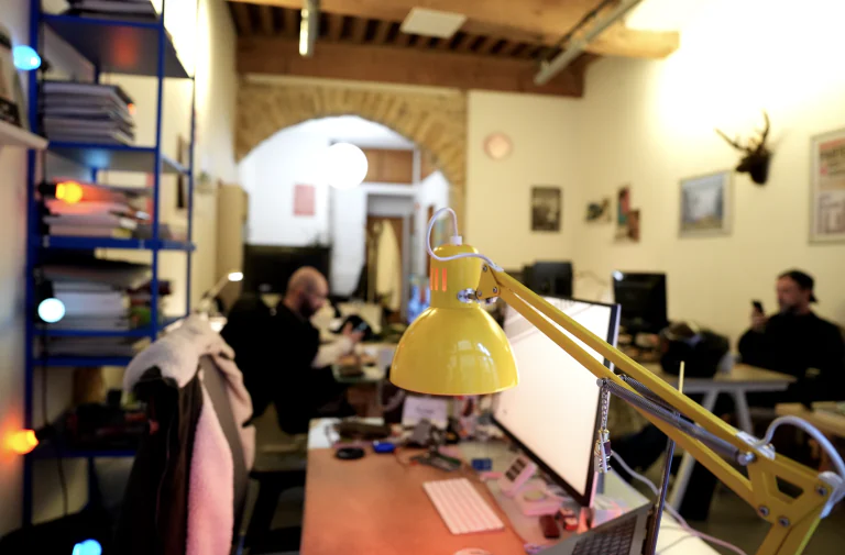 Les bureaux et leurs lampes sous les poutres du coworking
